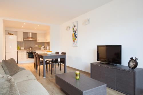 a living room with a couch and a table with a television at Apartaments Les Terrasses del Tarter in El Tarter
