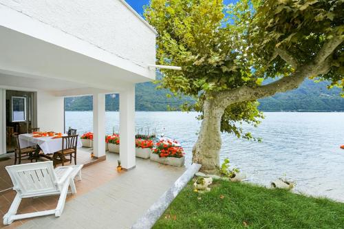 a white house with a table and chairs and a tree at Villa L'Approdo in Porlezza
