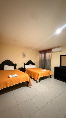a hotel room with two beds with orange sheets at Hotel Boutique Los Laureles in Tuxtla Gutiérrez