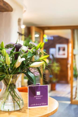 a vase of flowers sitting on a table with a sign at Royal Seven Stars Hotel in Totnes