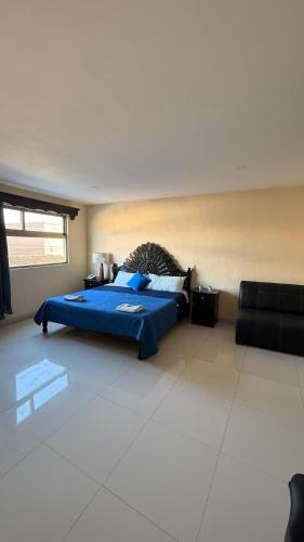 a bedroom with a blue bed and a couch at Hotel Boutique Los Laureles in Tuxtla Gutiérrez