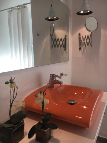 een oranje wastafel in een badkamer met een spiegel bij Helts B&B - Helts Guesthouse in Herning