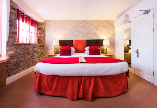 a large bedroom with a large bed with red sheets at Royal Seven Stars Hotel in Totnes