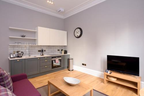 a living room with a kitchen and a clock on the wall at Destiny Scotland - Distillers House in Edinburgh