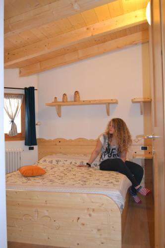 a woman sitting on a bed in a bedroom at Camping Al Lago Ledro in Ledro