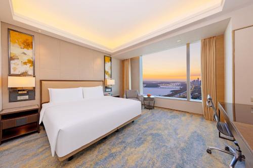 a bedroom with a large white bed and a large window at Shangri-La Songbei, Harbin in Harbin