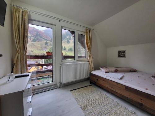 a bedroom with a bed and a large window at Diana's Holiday Home in Podu Dîmboviţei