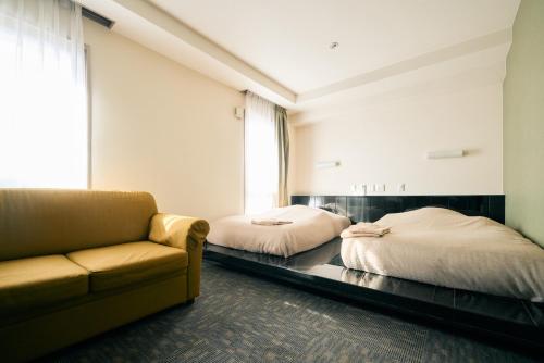 a living room with two beds and a couch at Urbain Hiroshima Executive in Hiroshima