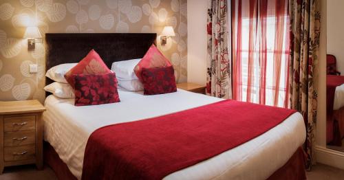 a hotel room with a large bed with red pillows at Royal Seven Stars Hotel in Totnes