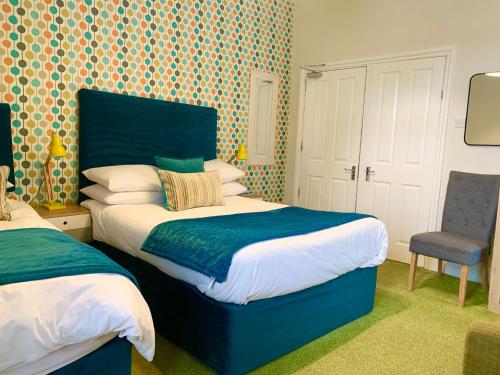 a bedroom with two beds and a chair at The Fylde International Guest House in Blackpool