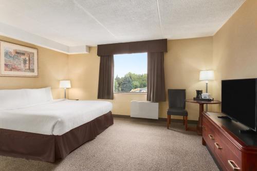 a hotel room with a bed and a flat screen tv at Days Inn by Wyndham Fallsview in Niagara Falls