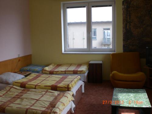um quarto com 3 camas, uma janela e uma cadeira em Na 15 Kopách em Kolín