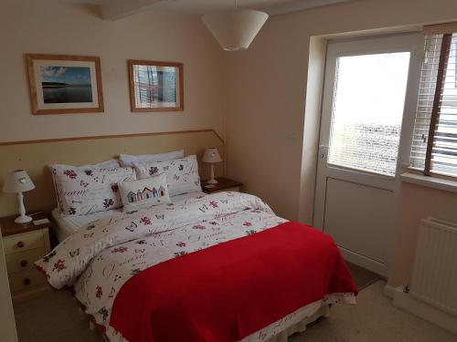 a bedroom with a bed with a red blanket and a window at The Trelinda Guest House in Newquay