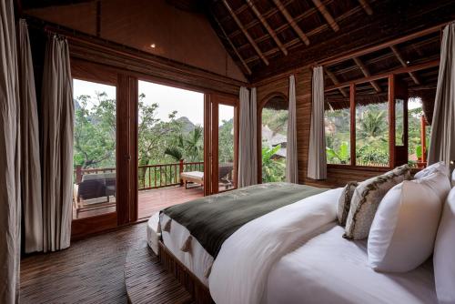 a bedroom with a large bed and a balcony at Lamia Bamboo Retreat Ninh Binh in Ninh Binh
