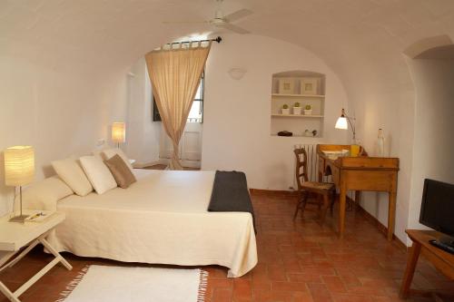 a bedroom with a bed and a table and a desk at Hotel la Plaça Madremanya in Madremanya