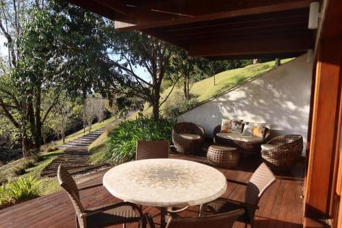 a patio with a table and chairs on a wooden deck at Hortênsia Boutique - Chalés de Luxo & Suítes Privativas in Campos do Jordão
