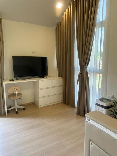 a living room with a tv and a desk and a window at 20 Tree Ville in Ban Ko