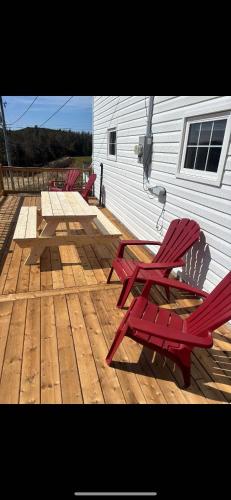three red chairs sitting on a wooden deck at Salty B'y Cottage in Twillingate