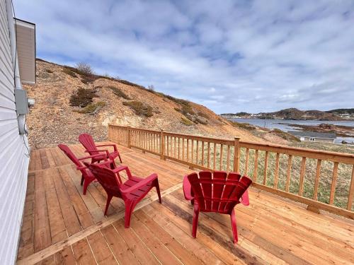 three chairs and a table on a wooden deck at Salty B'y Cottage in Twillingate