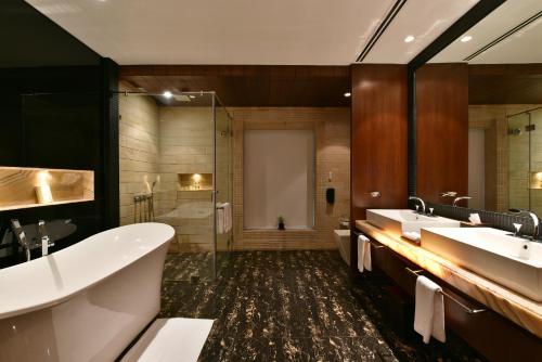 ein Badezimmer mit zwei Waschbecken, einer Badewanne und einer Dusche in der Unterkunft Della Resorts in Lonavla