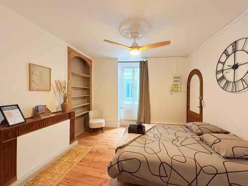 a bedroom with a bed and a clock on the wall at La Parenthèse à Foix in Foix