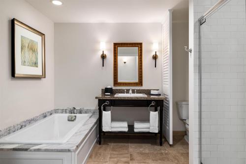 a bathroom with a tub and a sink and a mirror at Wild Dunes Resort - Residences at Sweetgrass in Isle of Palms
