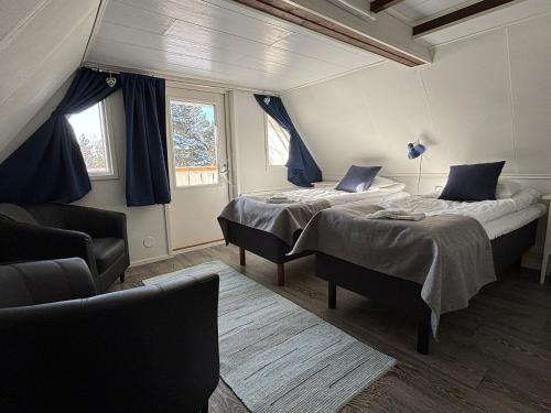 a bedroom with two beds and a couch and two windows at Arctic Lodge Hetan Kota in Enontekiö