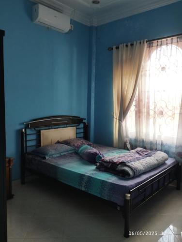 a bed in a blue room with a window at Penginapan Verlo in Payakumbuh
