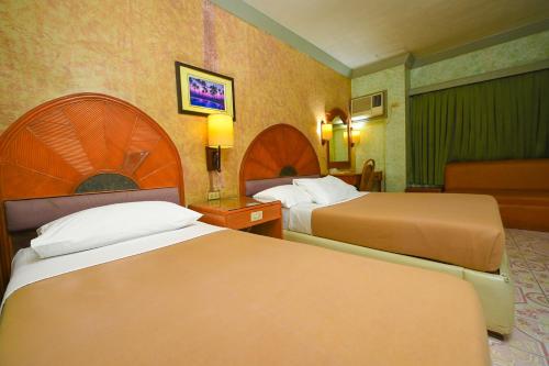 a hotel room with two beds and a chair at Grand City Hotel Inc. in Cagayan de Oro
