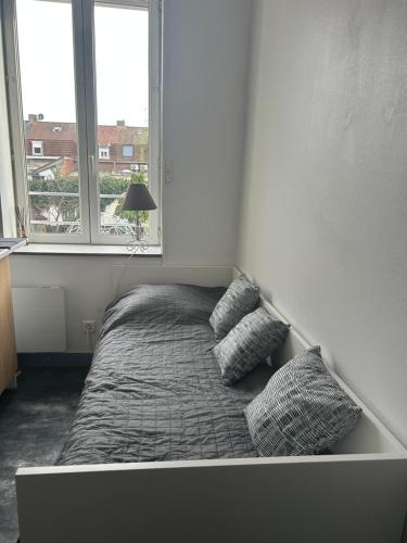 a bed with two pillows in a room with two windows at Petite chambre in Halluin