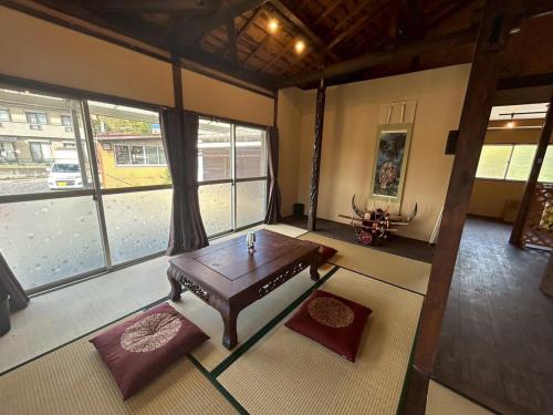 a living room with a table and some windows at Kominka Himejuku in Tajimi