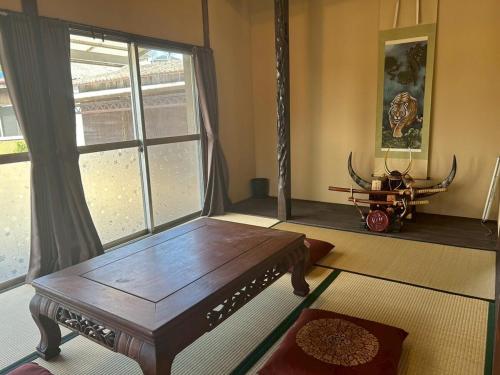 a living room with a wooden table and a window at Kominka Himejuku in Tajimi