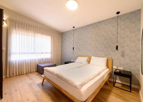 a bedroom with a large bed and a window at אחוזת נופש ביער -ווילה עם בריכת ספא וזרמי עיסוי in Ma'alot Tarshiha
