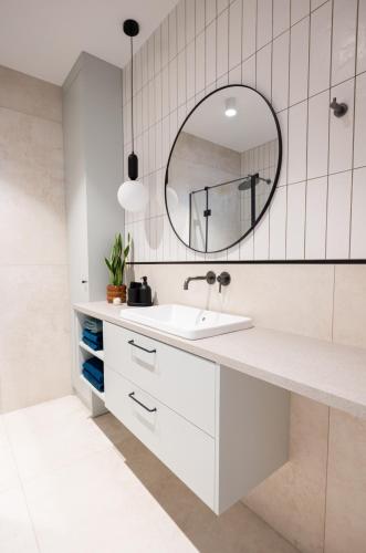a white bathroom with a sink and a mirror at Apartament D&Z in Elblag