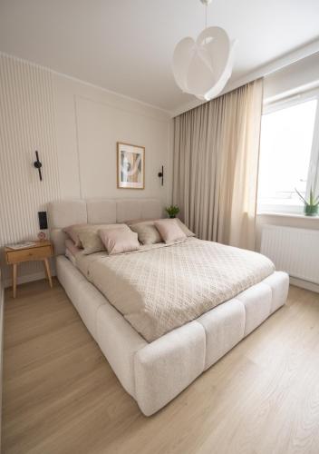 a large white bed in a white bedroom with a window at Apartament D&Z in Elblag