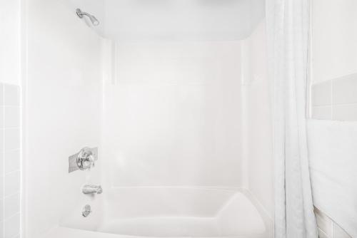 Un baño blanco con lavabo y ducha. en Knights Inn Pine Grove, en Pine Grove