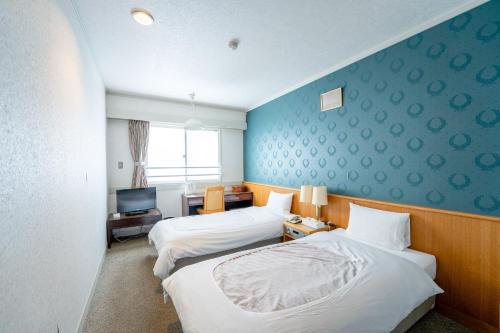 a hotel room with two beds and a television at Asoviva Nagano Park in Nagano