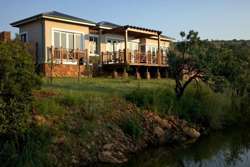 a house on a hill with a river in front of it at Mount Grace Hotel & Spa in Magaliesburg
