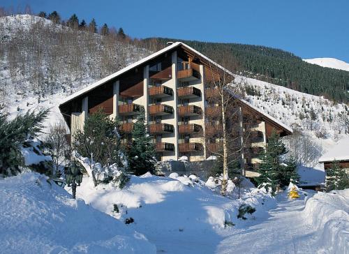 a large building in the snow with snow covered trees at Catrina Hotel in Disentis