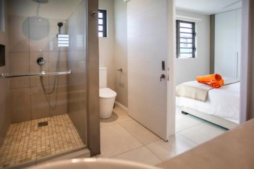 a bathroom with a shower and a toilet and a bed at Salty Sands Studio in Rivière Noire