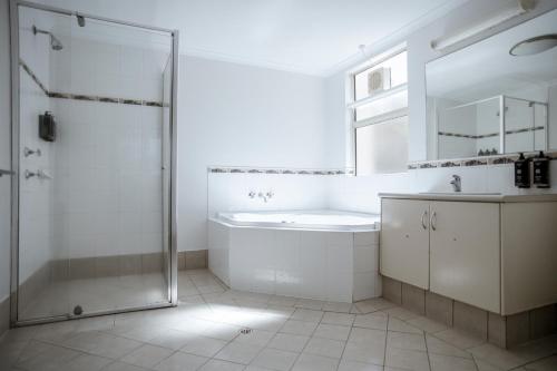 a white bathroom with a shower and a sink at Kalbarri Edge Resort in Kalbarri