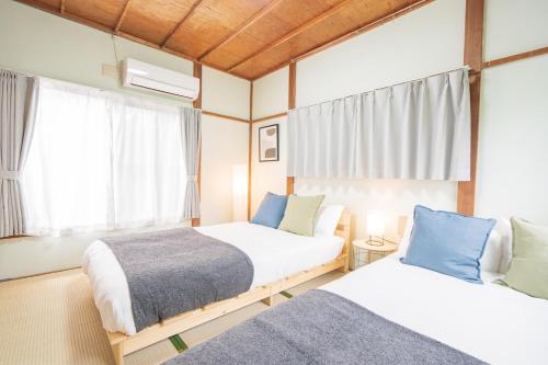 a bedroom with two beds and a window at Yokosuka Guest House in Yokosuka
