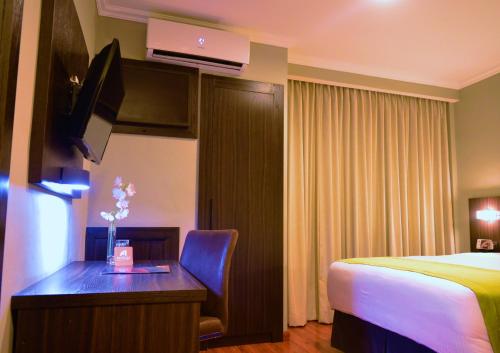 a hotel room with a bed and a desk with a computer at Aranjuez Hotel & Suites in David