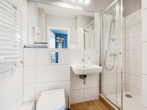 a white bathroom with a toilet and a sink at Villa Milla in Łeba