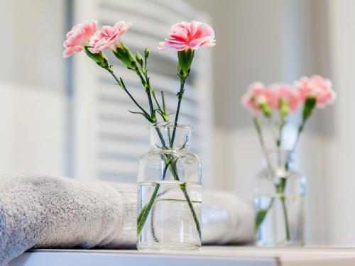 two vases with pink flowers in them on a table at Villa Milla in Łeba