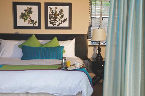 a bedroom with a bed with green and white pillows at Mount Grace Hotel & Spa in Magaliesburg