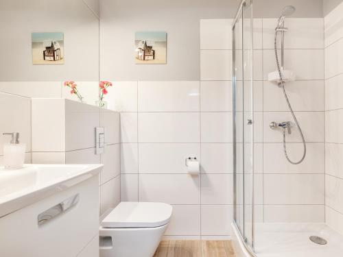 a white bathroom with a shower and a toilet at Villa Milla in Łeba