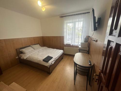 a bedroom with a bed and a table and a window at Бордуляка 11 in Ternopil