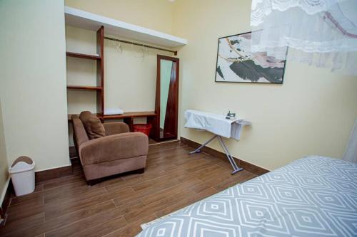 a bedroom with a bed and a chair and a table at Nadyapartment in Dodoma
