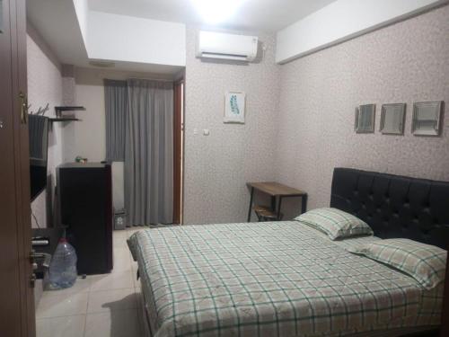 a bedroom with a bed with a green plaid blanket at Japlen Room in Pondokcabe Hilir